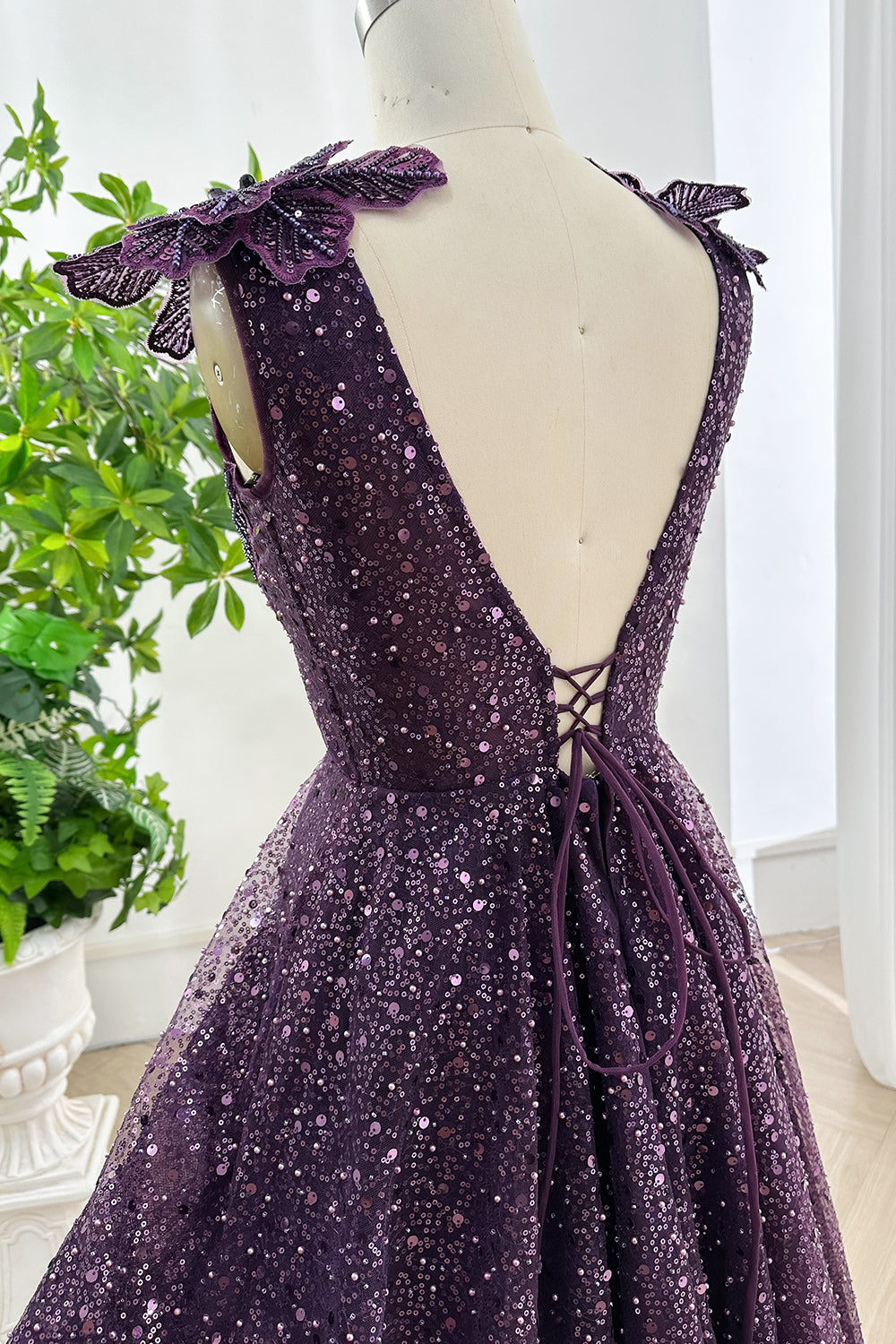 Back view of purple sequin gown with open V design and adjustable lace up corset tie highlighting elegant tailoring