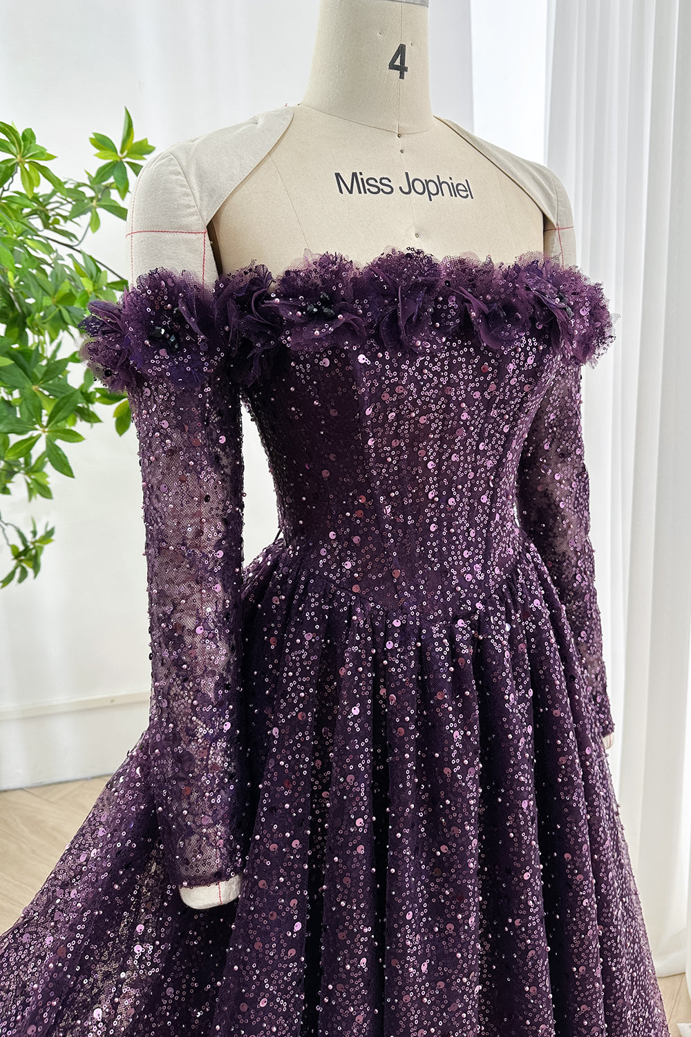 Off-shoulder dark purple sequin gown with fitted long sleeves, floral ruffle neckline, and flowing skirt for elegant evening events