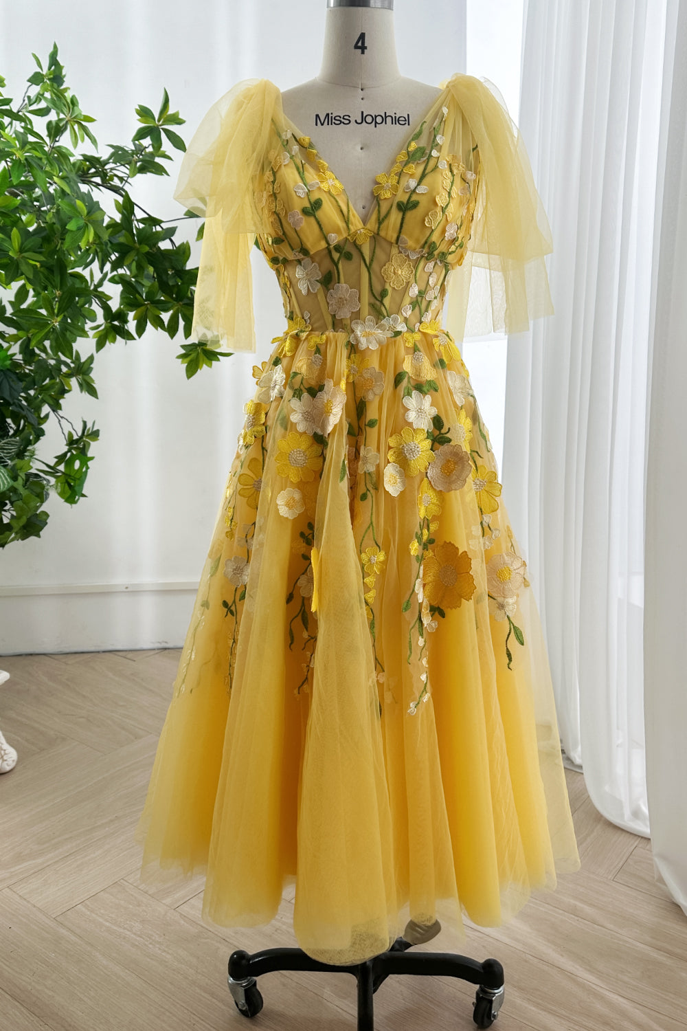 Marigold couture delicate appliqué gown shown front view highlighting structured bodice botanical detailing airy sleeves softly arranged