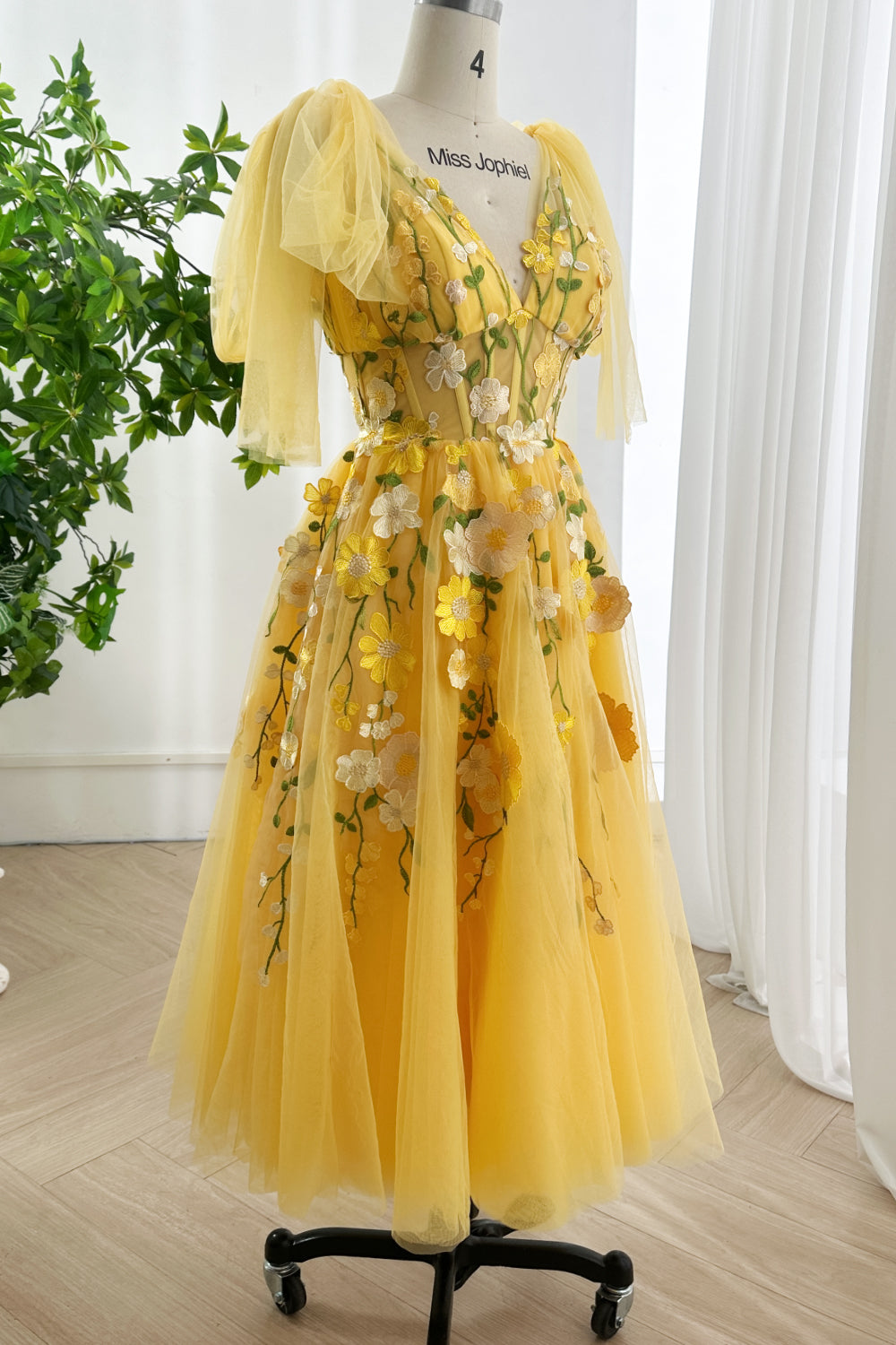 Golden fairytale artisan dress presented angled perspective featuring enchanting vines intricate blossoms floating softness gracefully illuminated