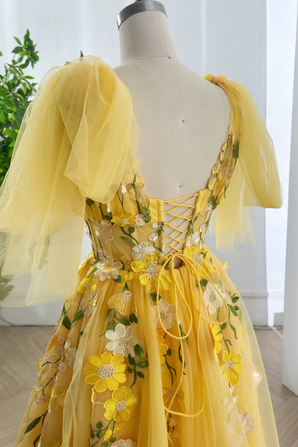 Buttercup laceup back gown revealing sculpted silhouette enhanced by blossoming motifs trailing gracefully across sheer layered textiles