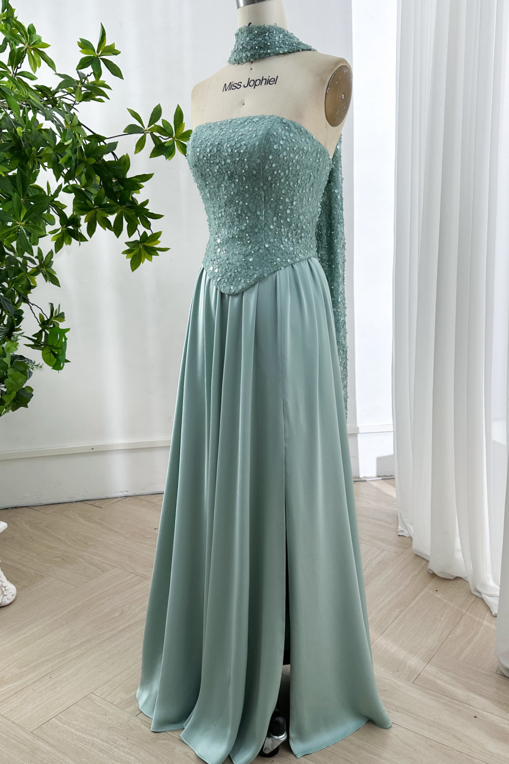 Serene pastel ensemble featuring intricate sparkled surface merging tailored waistline and fluid drape photographed near verdant leaves indoors