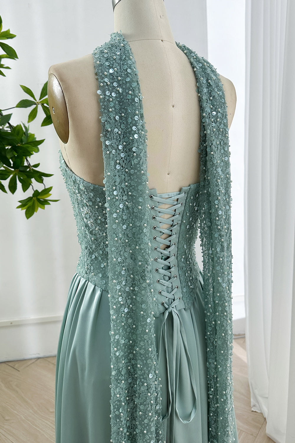 Elegant lace up back panel adorned with textured shimmering scarf extensions cascading effortlessly displaying artisanal construction eveningwear