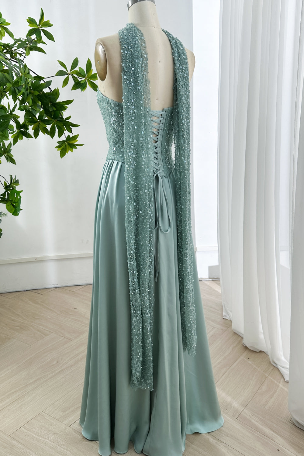 Graceful rear view mint silhouette featuring expansive sequined drape accents harmonizing with sleek skirt volume creating poised impression