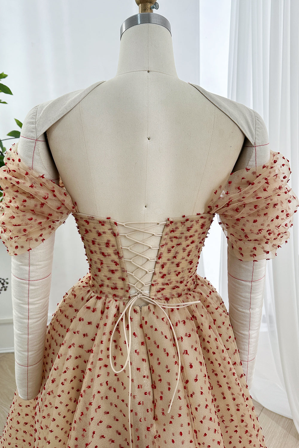 Elegant cinched waist prom attire displaying beautiful draped mesh layering and professional garment construction from a rear view.