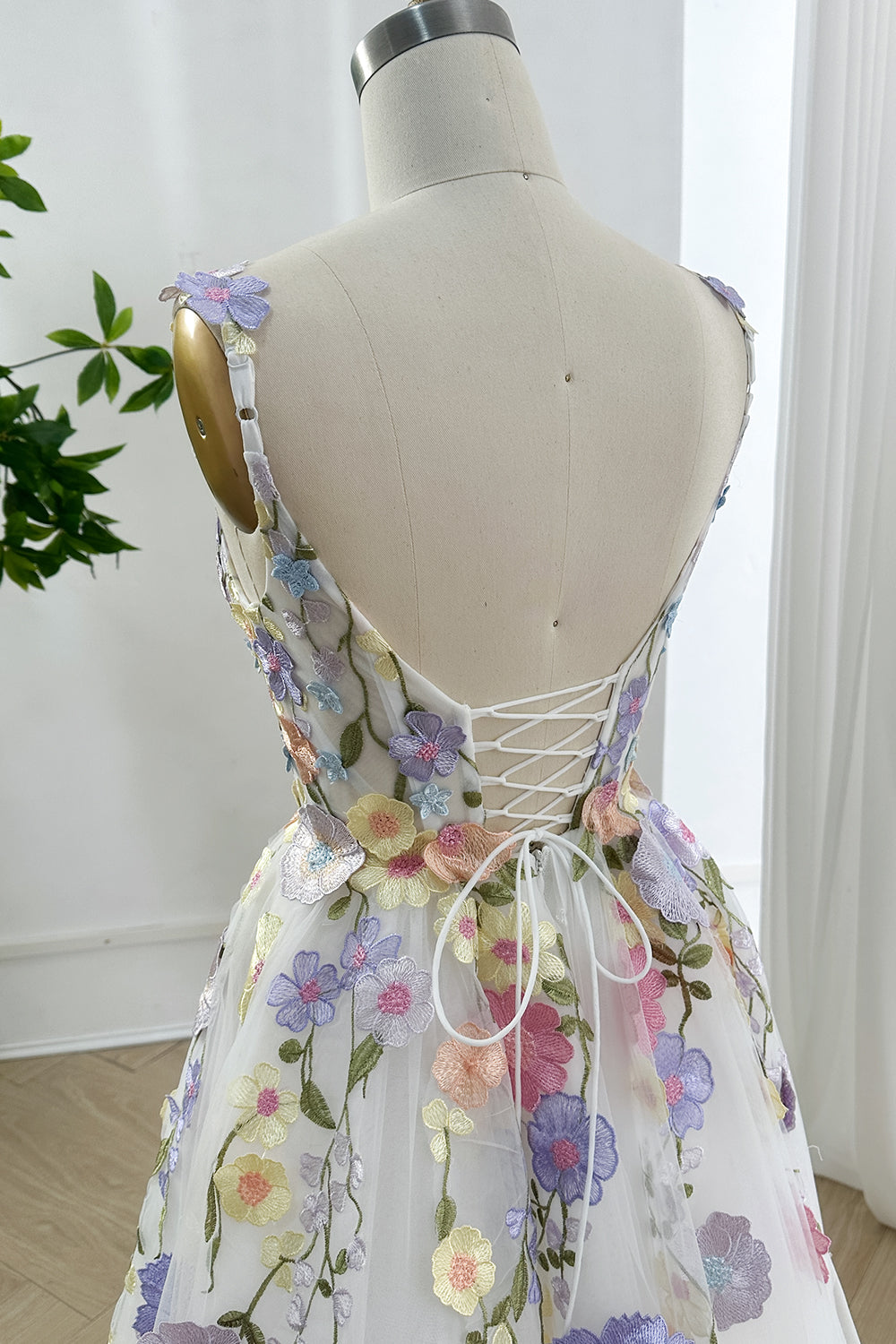 Adjustable lacing embroidered back detail elegance displayed rear perspective focusing structural corsetry pastel florals graceful tailoring harmony