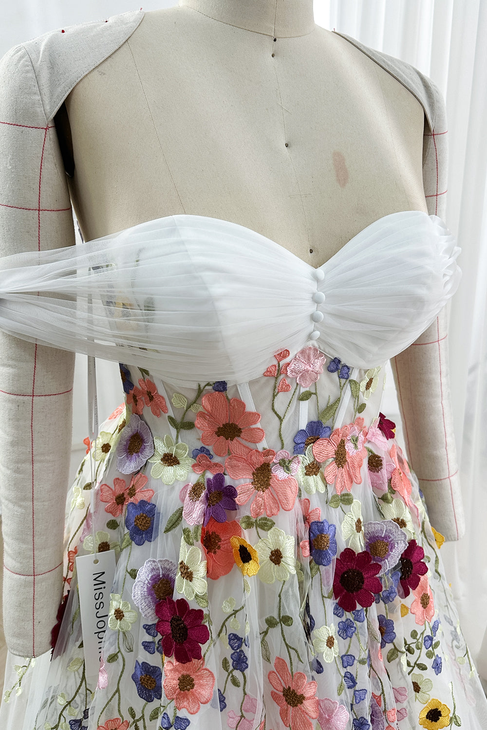Sweetheart ruched bodice adorned vibrant appliques showcasing intricate stitching detail within luminous studio environment
