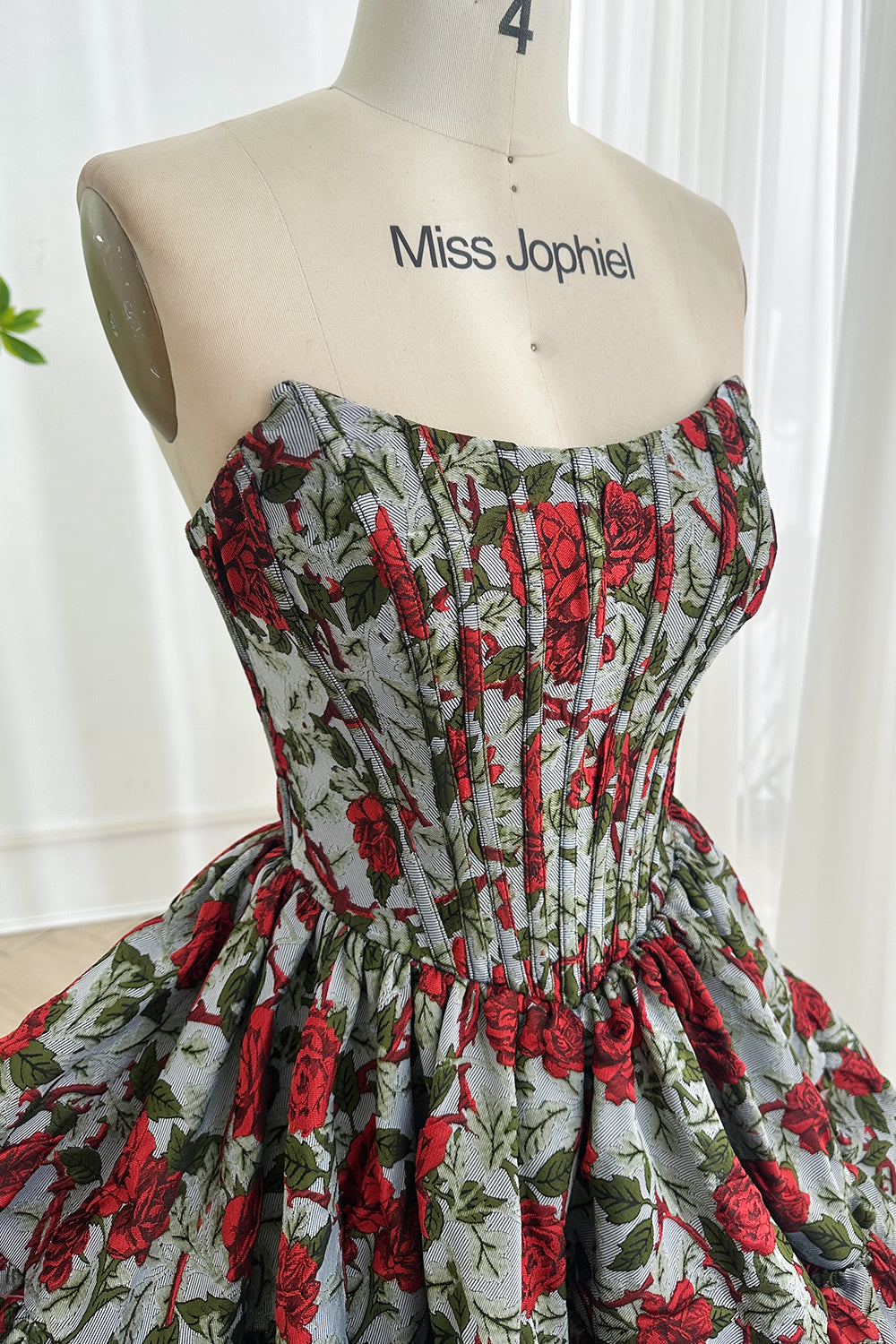 Structured bustier rose brocade homecoming attire featuring straight neckline defined waist dramatic layered hem closeup view