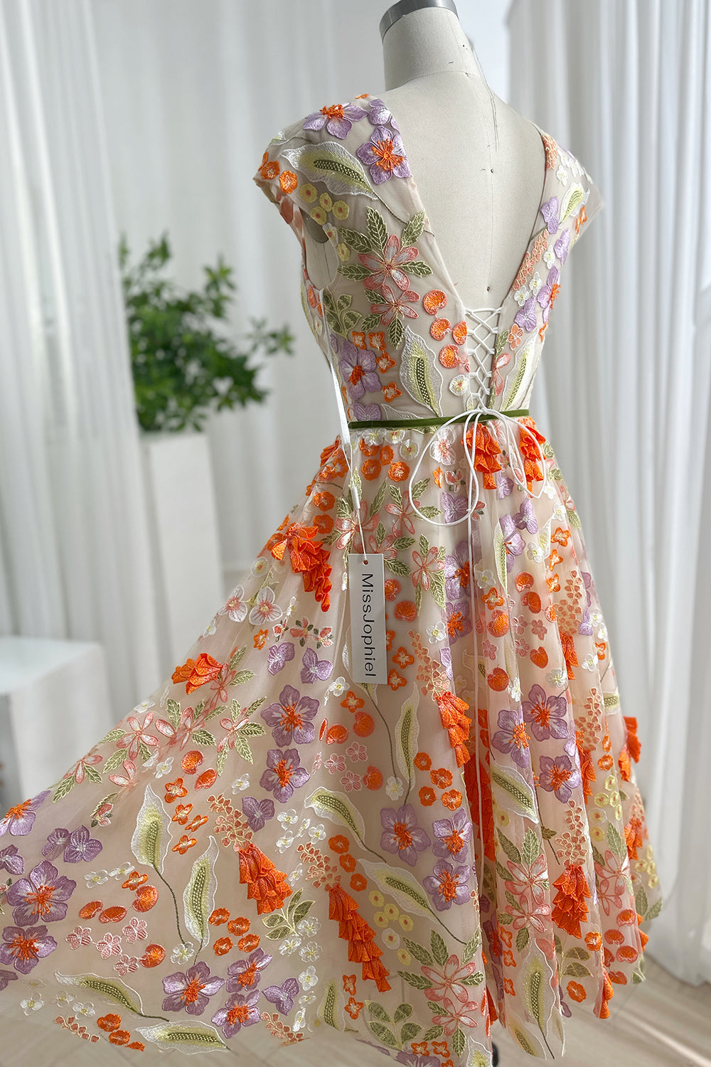 Whimsical flower pattern tea garment rear perspective highlighting vivid foliage motifs artistic layering graceful drape couture texture