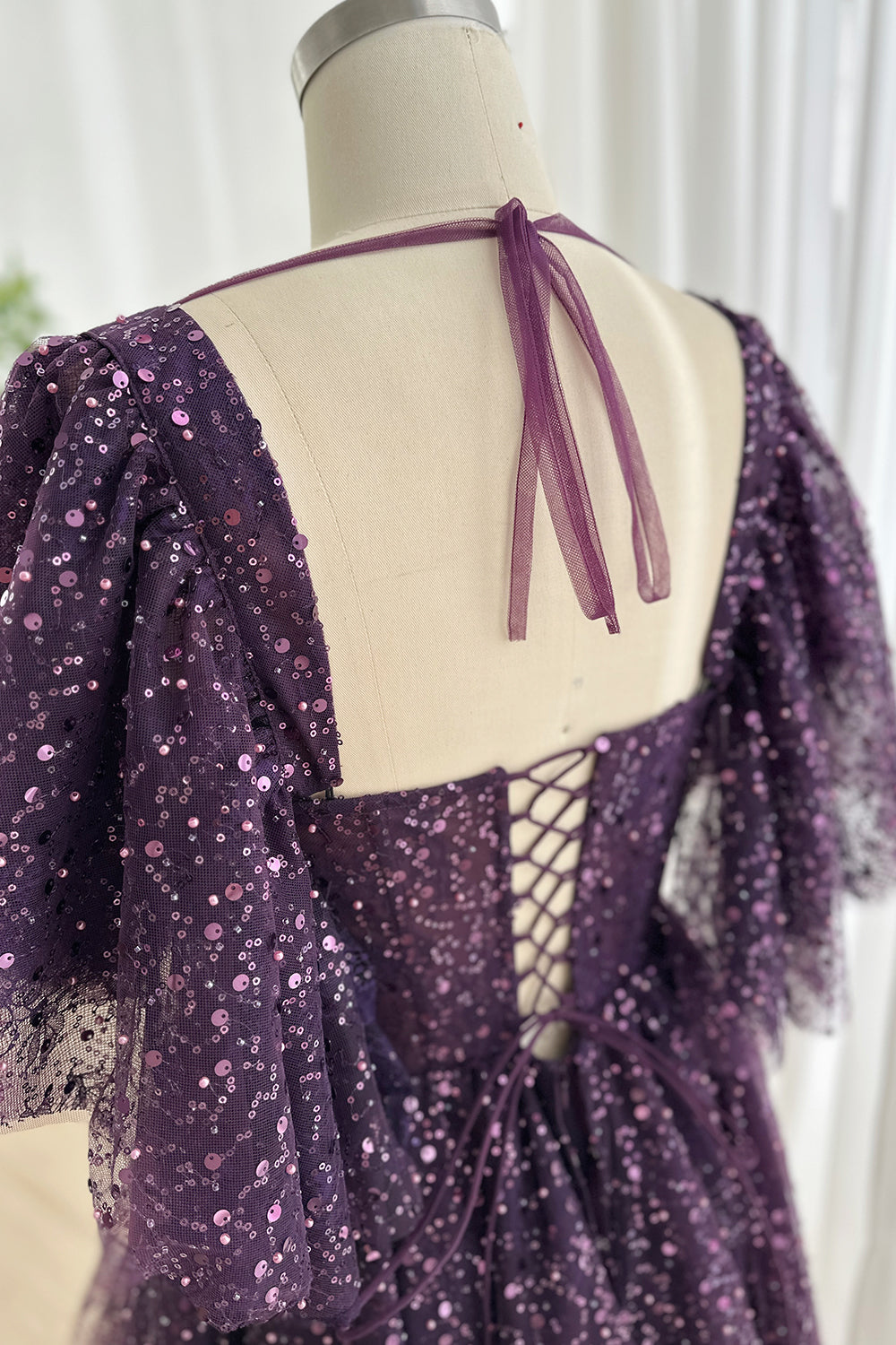 Sheer sleeve back tie tulle feature emphasizing lightweight fabric transparency soft drape adjustable ribbon fastening refined craftsmanship scene