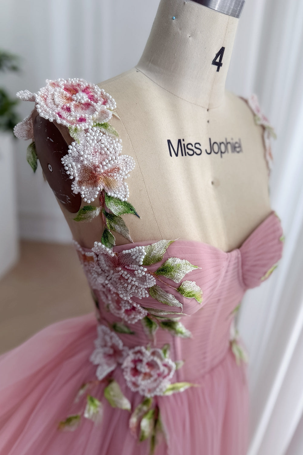 Closeup beaded petal embroidery, ruched cups, botanical accents across romantic pink quinceanera party attire, detail focus..