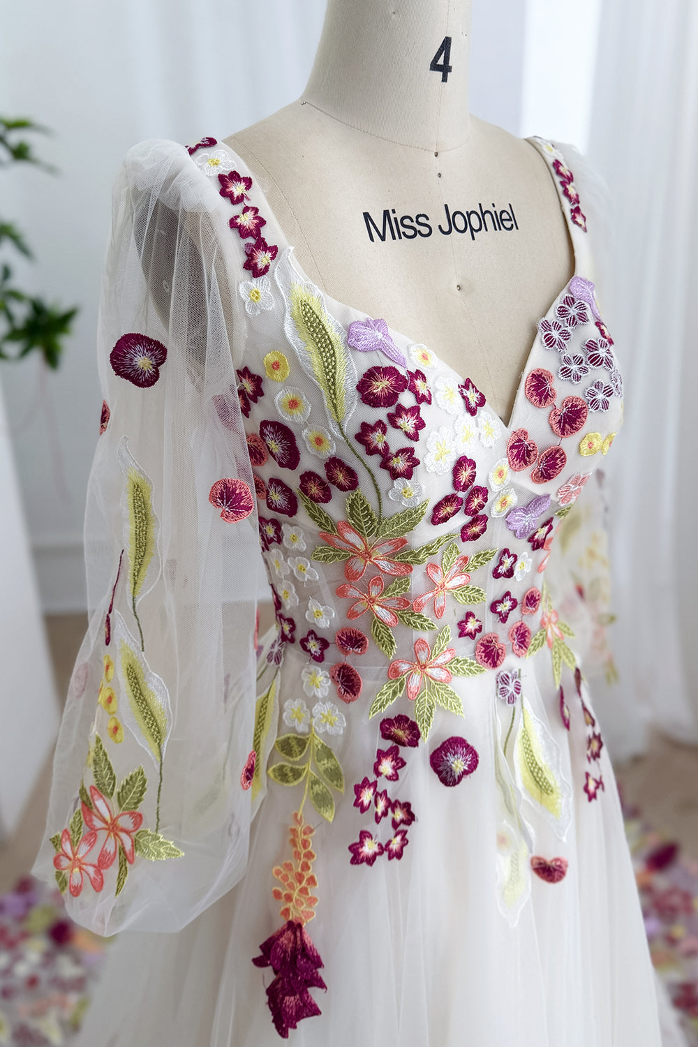 Delicate sweetheart bodice showcasing vivid appliques surrounding translucent puffed armcoverings beside refined mannequin