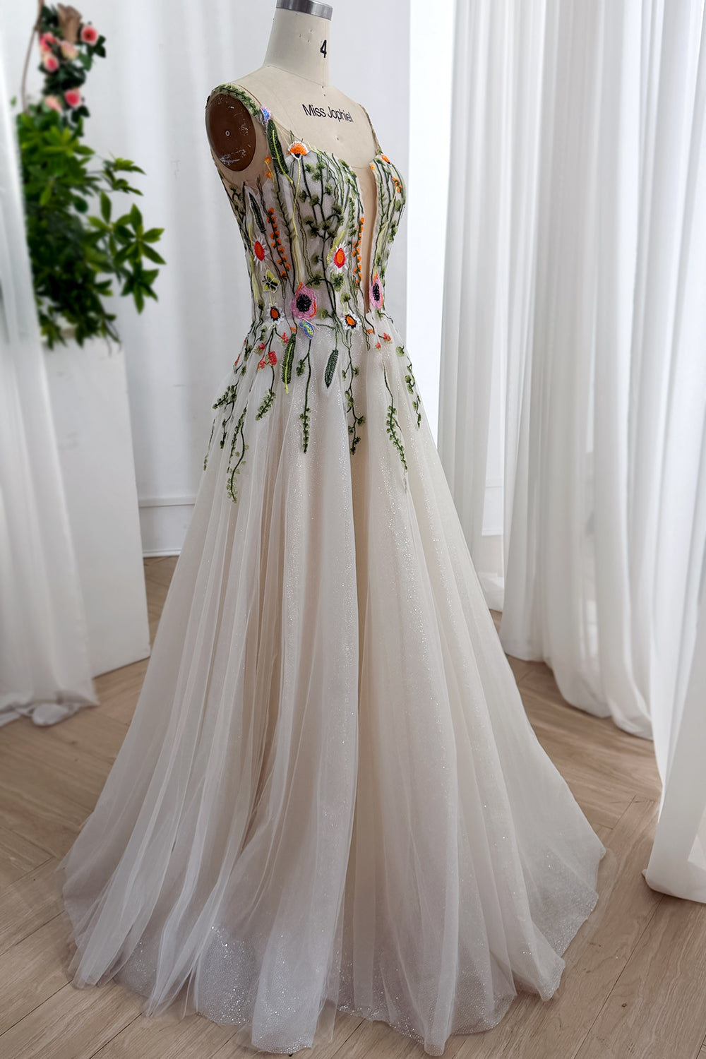 Angled portrait floral embroidered wedding ensemble structured basque waist colorful blossoms, soft chapel hemline, editorial
