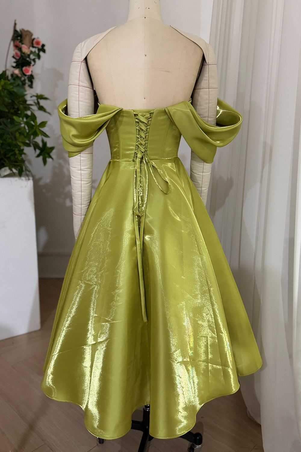 Rear perspective emphasizes highshine chartreuse skirt, crisscross ties, dropped sleeve loops, formal mannequin styling