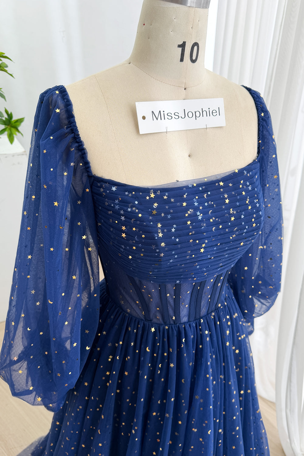 Close frontal portrait of sapphire starry prom attire featuring ruched neckline, transparent corset panels, structured waist.