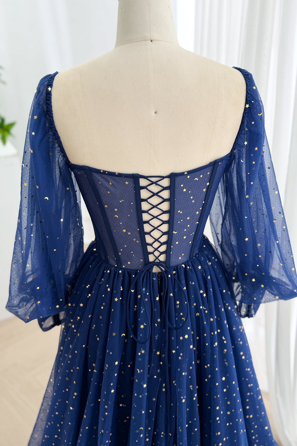 Rear view displays lace-up closure over sheer blue back, supportive boning, moon print bishop arms, romantic fit, airy charm.