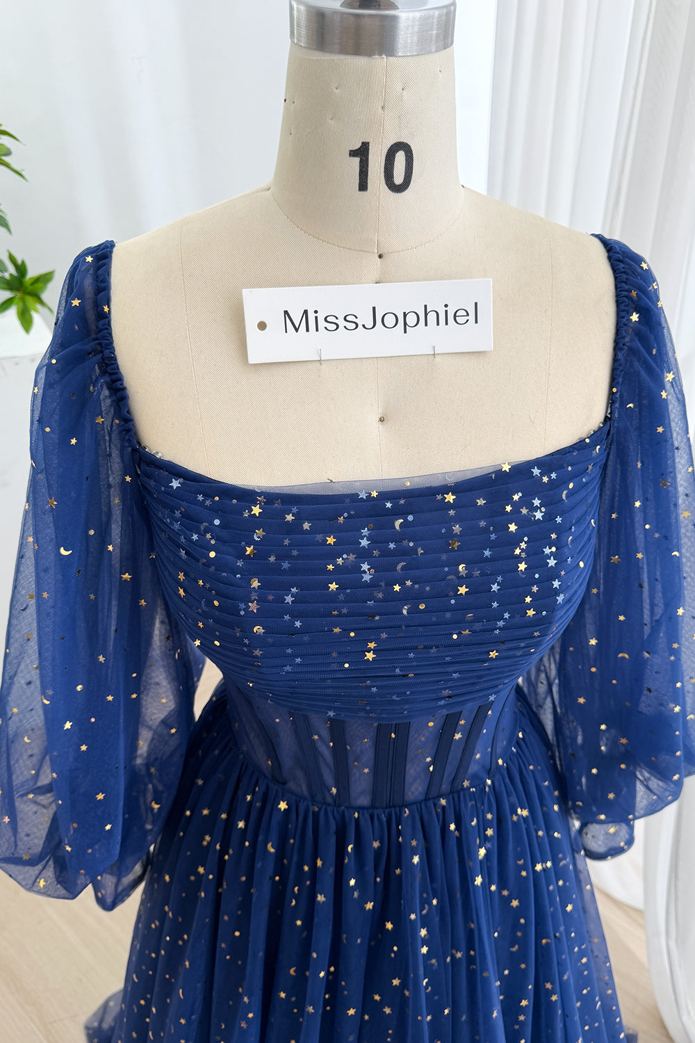 Detailed upper angle presents pleated bust, off-shoulder puff design, metallic motifs, elegant fantasy occasion look glamour.