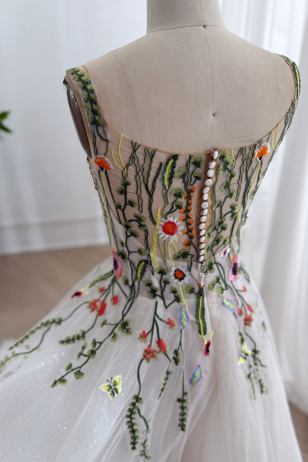 Rear floral mesh dress displays scoop back covered buttons zipper fitted waist delicate vines handmade finish close portrait.