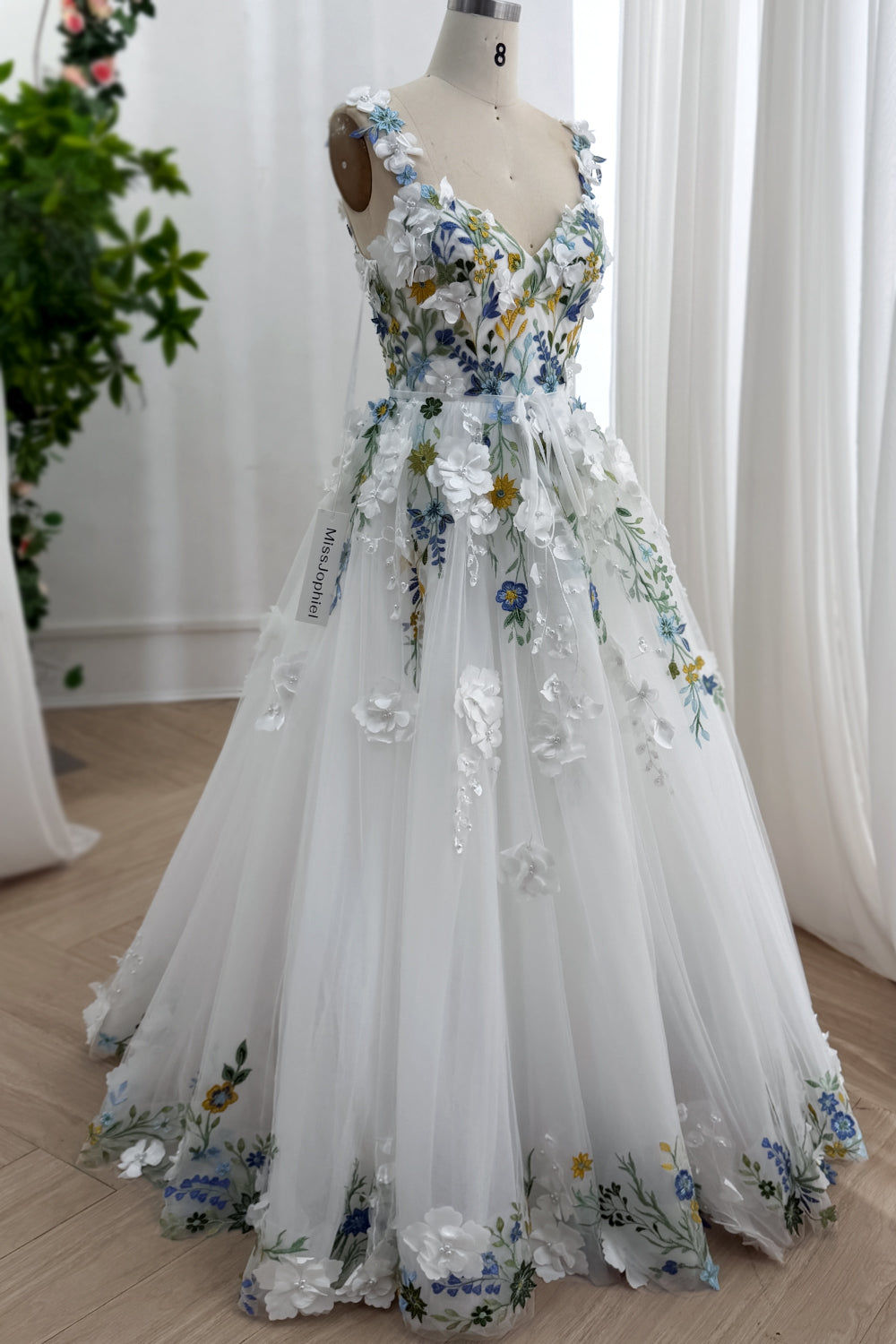 Whimsical princesswear featuring handcrafted petals cornflower detailing verdant accents flowing layers captured angled presentation