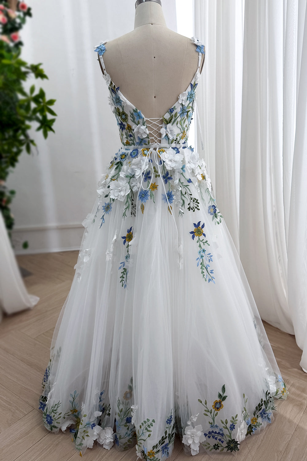 Dreamlike backside perspective revealing sweeping skirt silhouette decorative florals cascading hemline within studio setting