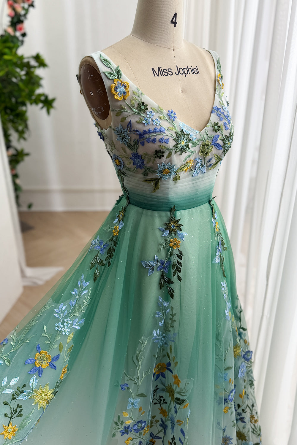 Mint-gradient botanical bodice closeup, sheer mesh panels, blue yellow blossoms, ruched waist, boutique window lighting aglow