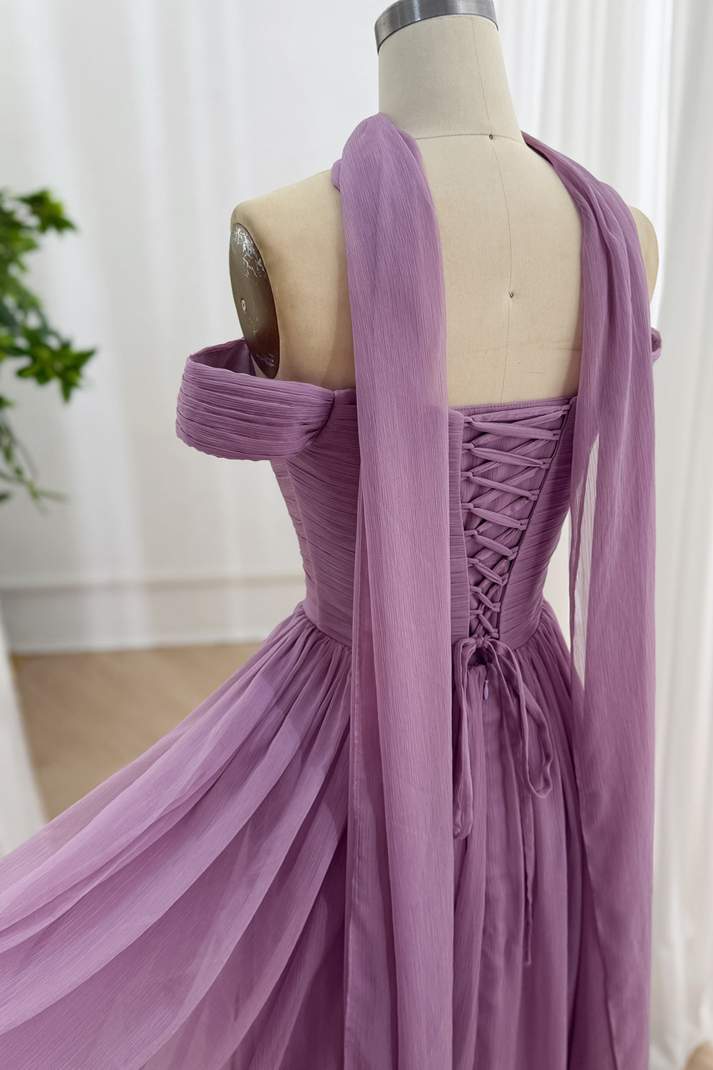 Back view highlights laceup closure, trailing neck ties, offshoulder armbands, pleated bodice, romantic eveningwear