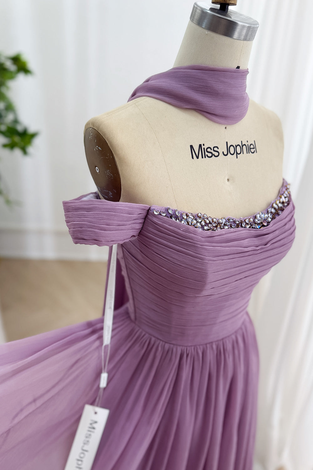 Closeup captures rhinestone embellished sweetheart bustline, textured lilac draping, delicate shoulder wrap details