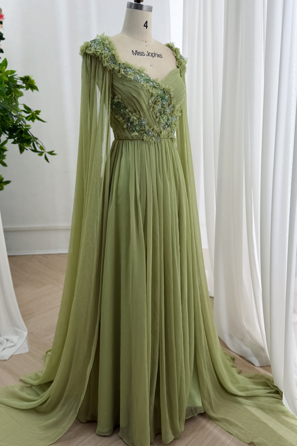 Angled front showcases asymmetrical wrap bust, dimensional ruffles, sparkling crystals, airy sleeves, reception elegance