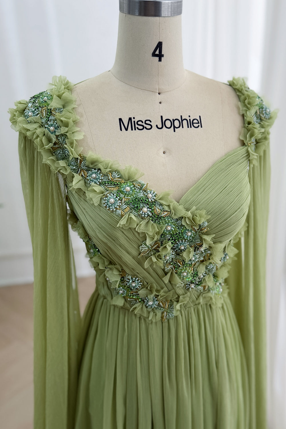 Closeup captures one-shoulder illusion, ornate appliques, textured pleats, mint sparkle, luxury photoshoot inspiration