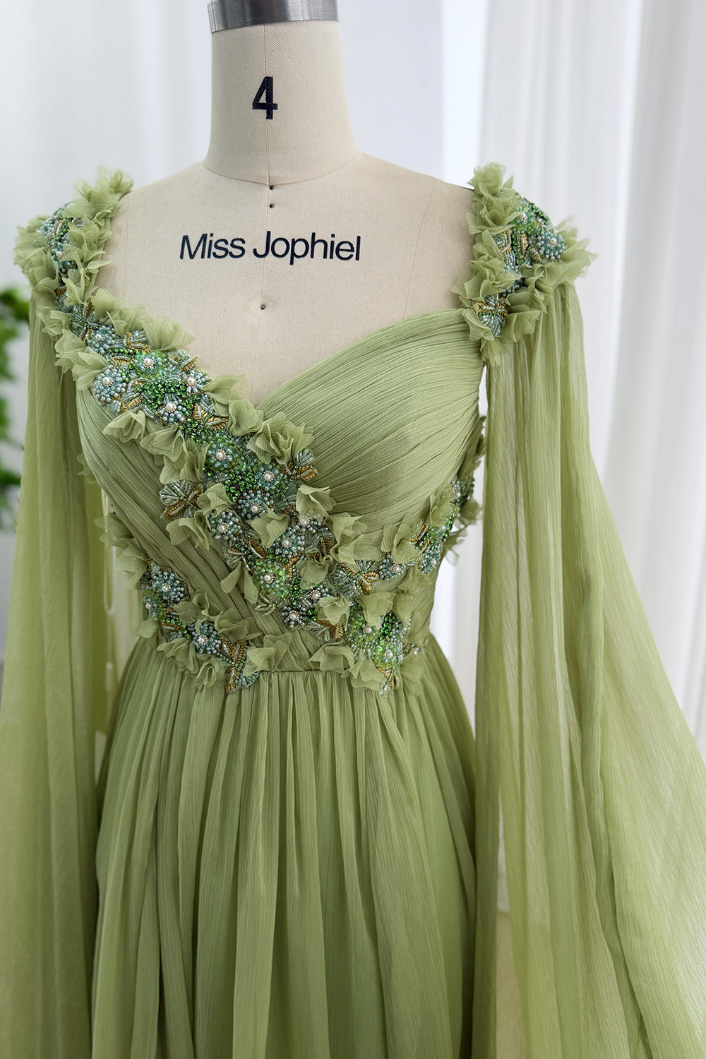 Sage pleated bodice gown featuring diagonal floral beadwork, cape sleeves, pearl accents, romantic prom styling details