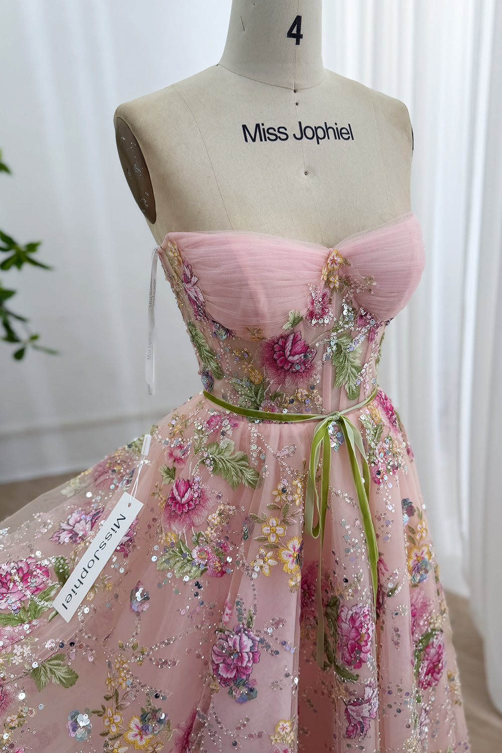Front portrait reveals rosy embroidered mesh dress, sculpted bustier, olive ribbon waist, romantic party ready silhouette fit