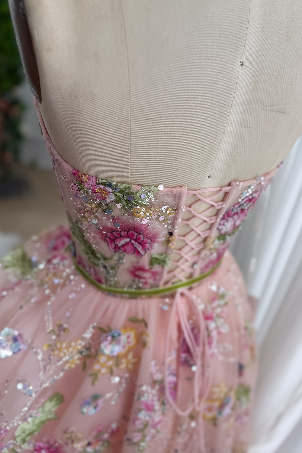 Rear closeup shows adjustable lacing, nude form, satin trim, rosette motif, rosewater boutique made to measure finish. polish