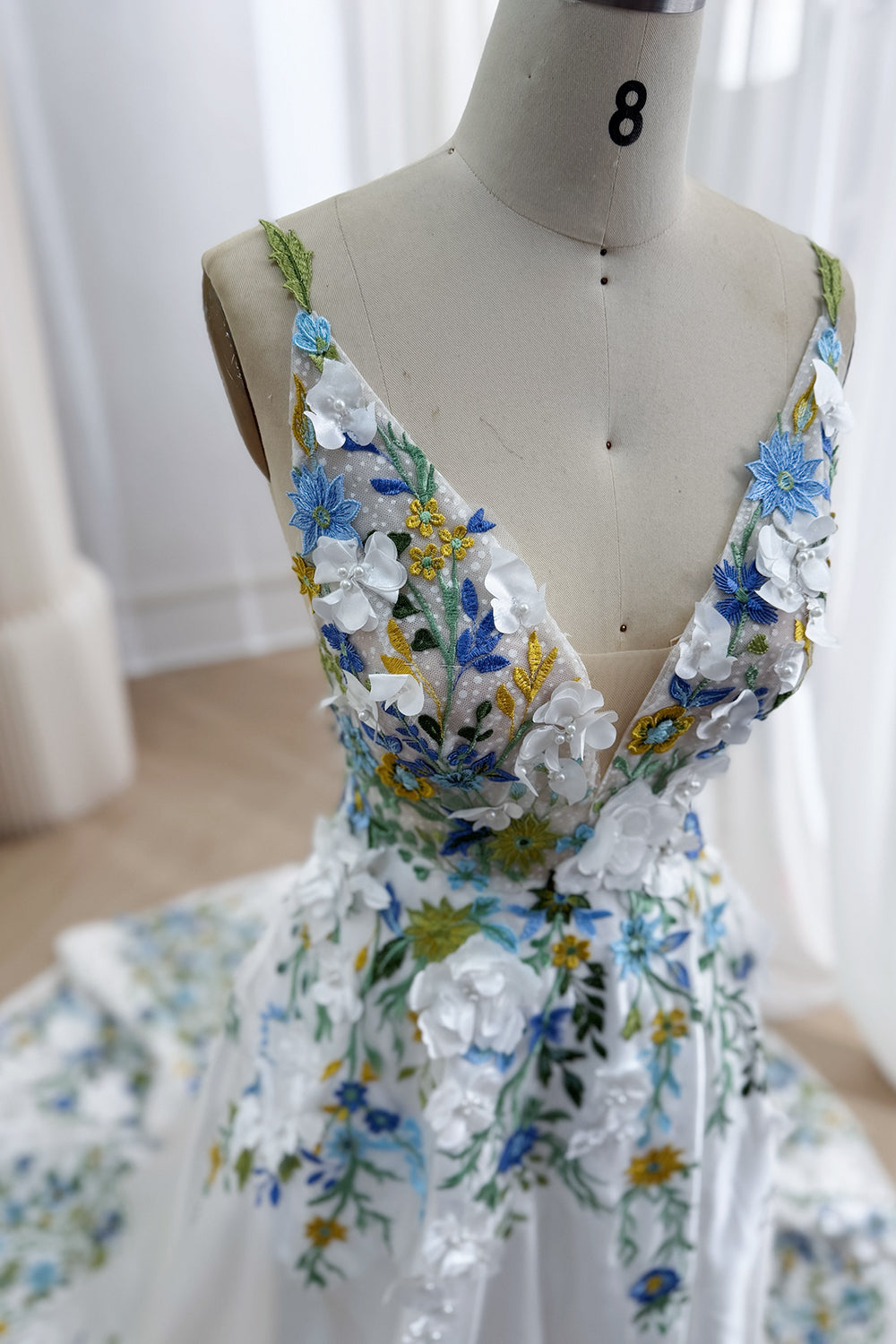 Three-quarter angle captures garden-inspired accents, golden flowers, emerald vines, sculpted corsage, trim chapel silhouette