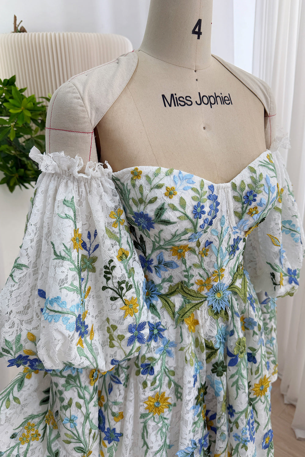 Angled portrait reveals cottagecore partywear, sculpted neckline, ruffled cuffs, multicolor blossoms, airy volume chic appeal