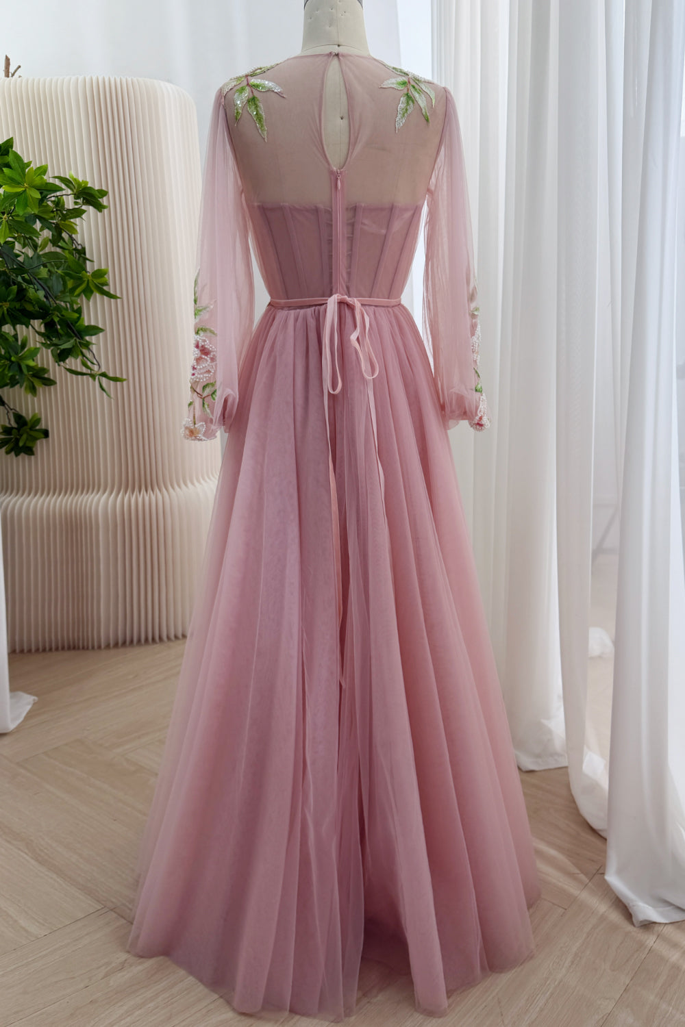 Rear perspective highlights teardrop keyhole, hidden zipper, boned corsetry, waist ties, flowing skirt, and translucent yoke.