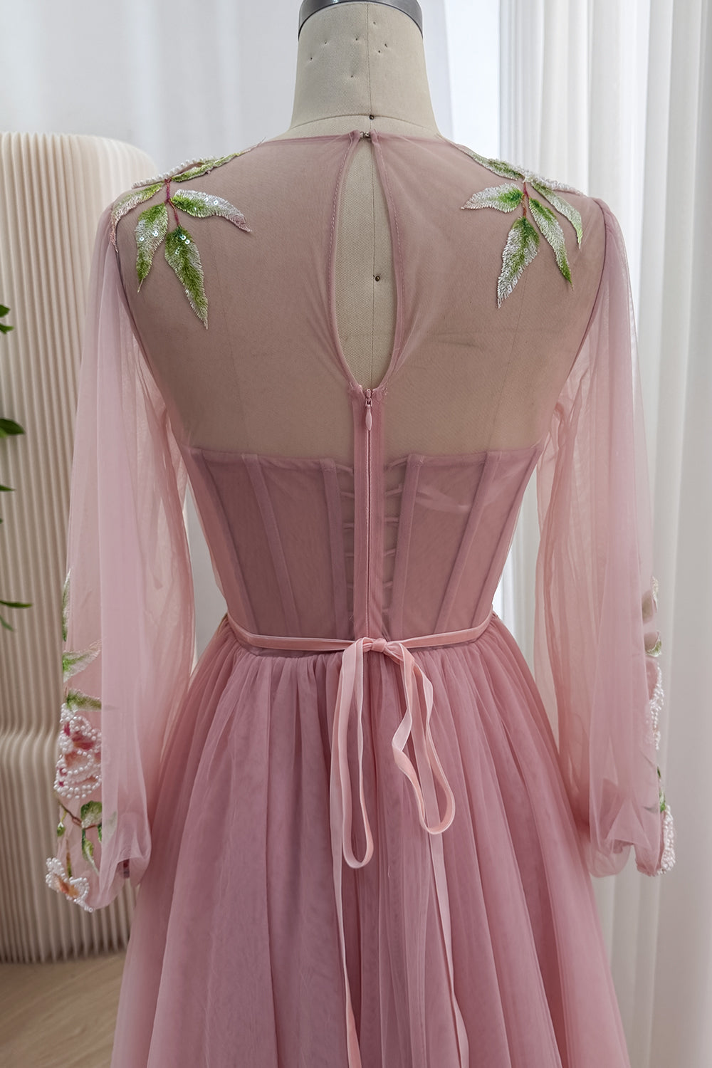 Reverse framing displays illusion upper panel, oval opening, structured stays, mid fastening, ribbon sash, embroidered cuffs.