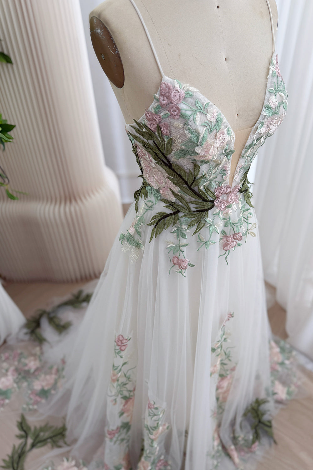 Angled portrait highlights illusion V-neckline, sculpted cups, verdant foliage, cascading blossoms, flowing A-line silhouette