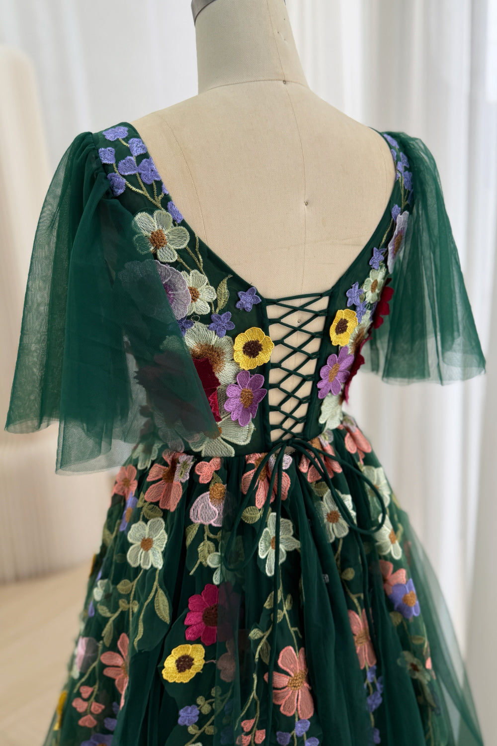 Back image reveals crisscross lacing, embroidered shoulder straps, translucent winged panels, garden-wedding evening ensemble