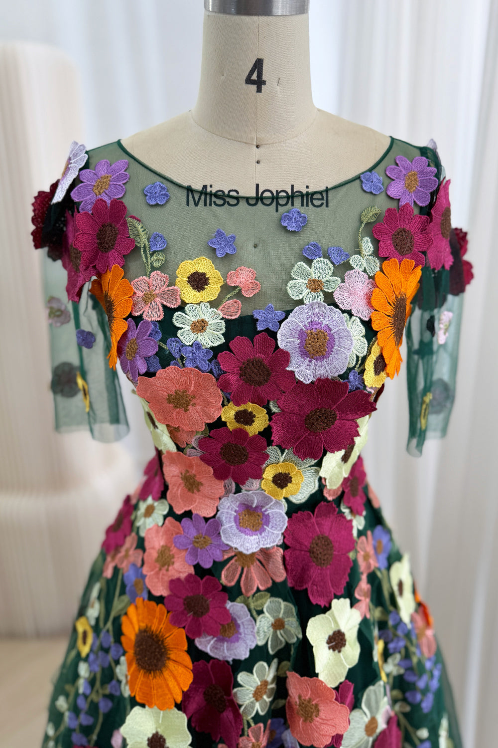 Close frontal detail highlights transparent bodice, round collar, dimensional wildflowers, sculpted fit, artisanal needlework