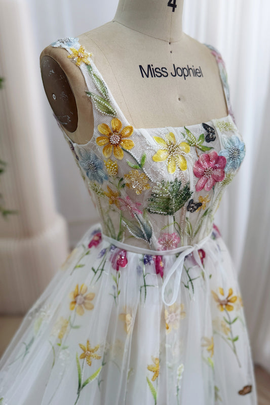Closeup showcases multicolor beadwork, blossoms, leafy embroidery, transparent boned corsetry across the ivory tulle overlay.