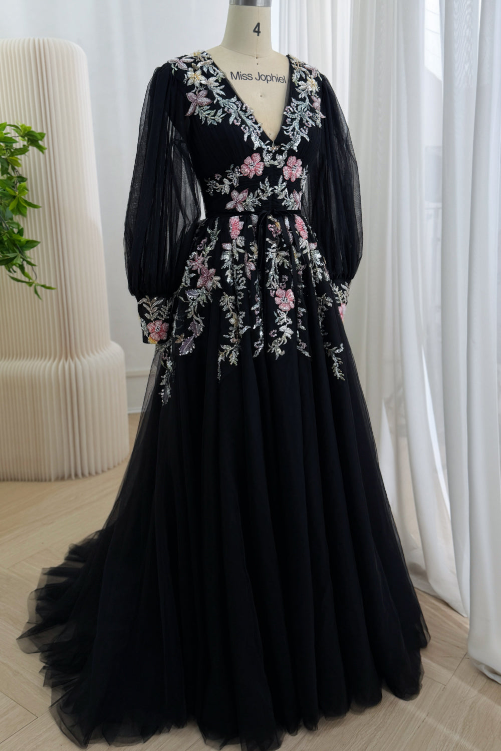 Full-length front view of the black embroidered tulle gown with long sheer sleeves and a flowing A-line skirt with sweep train