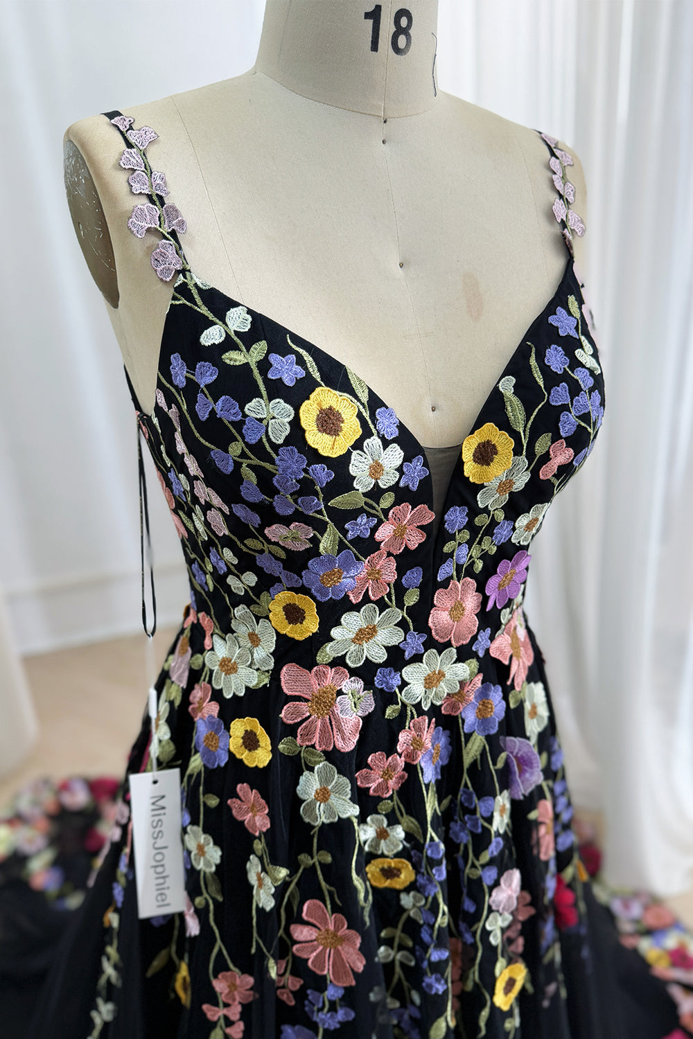 Close-up of black tulle bodice with vibrant multicolored floral embroidery and a plunging V-neckline.