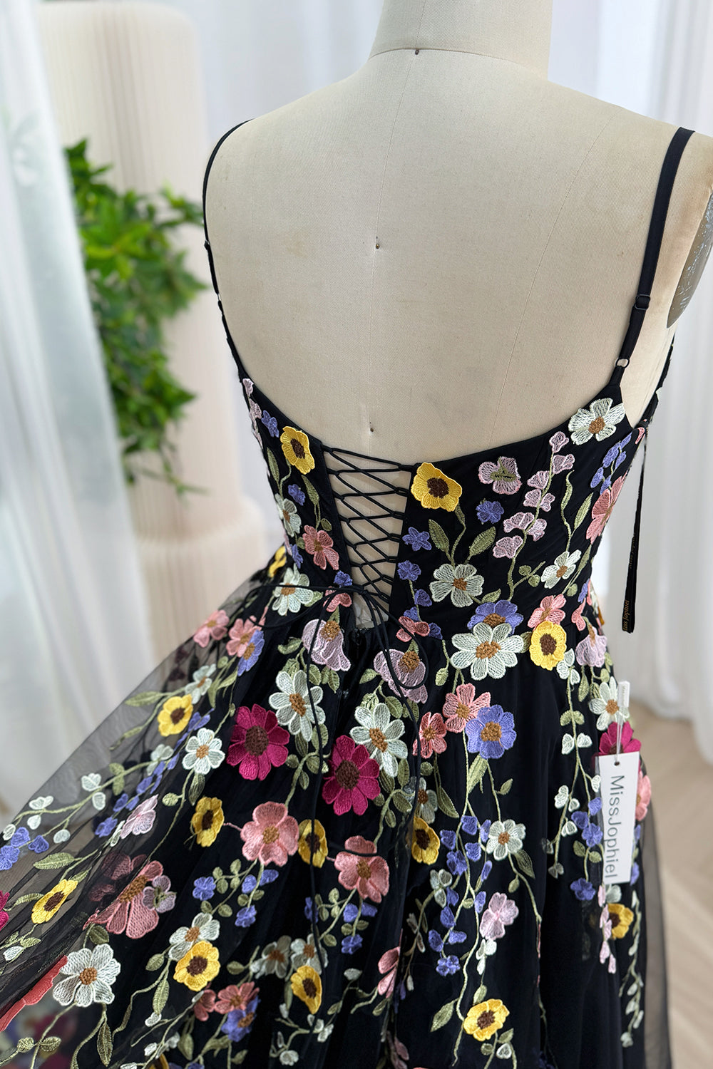 Close-up of the lace-up corset back on a black tulle dress with floral embroidery.