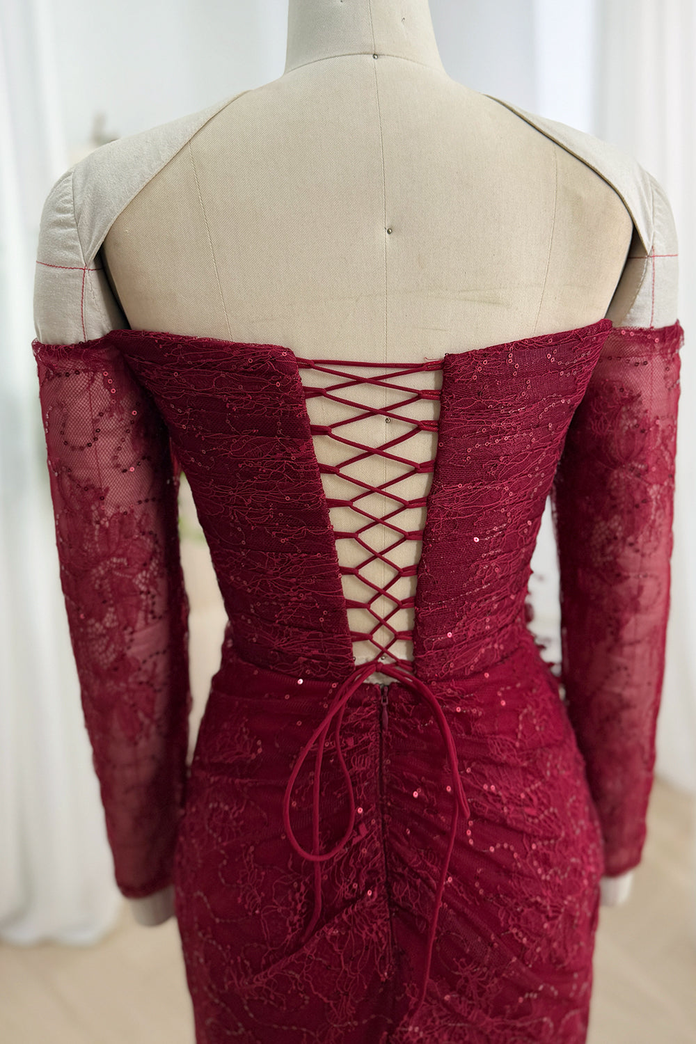 Close-up of adjustable lace-up back on burgundy off-the-shoulder sequin lace gown
