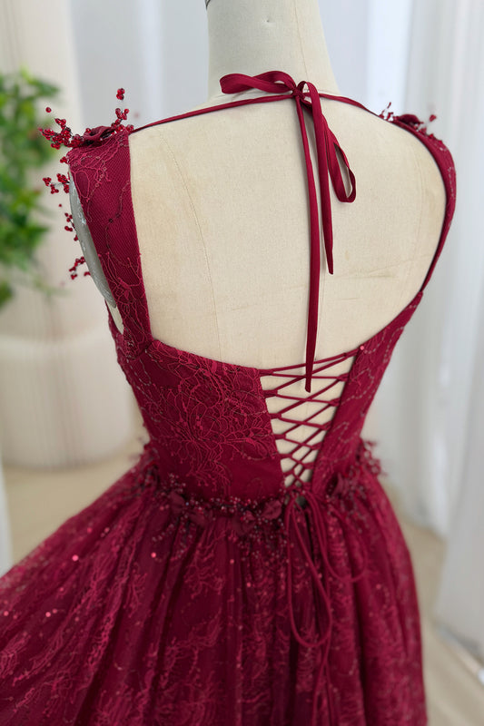 Close-up back view of the burgundy lace dress with an open back, neck tie, and corset lacing