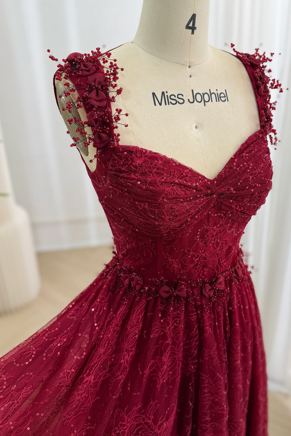 Close-up of a burgundy sequin lace sweetheart bodice with dimensional floral shoulder straps