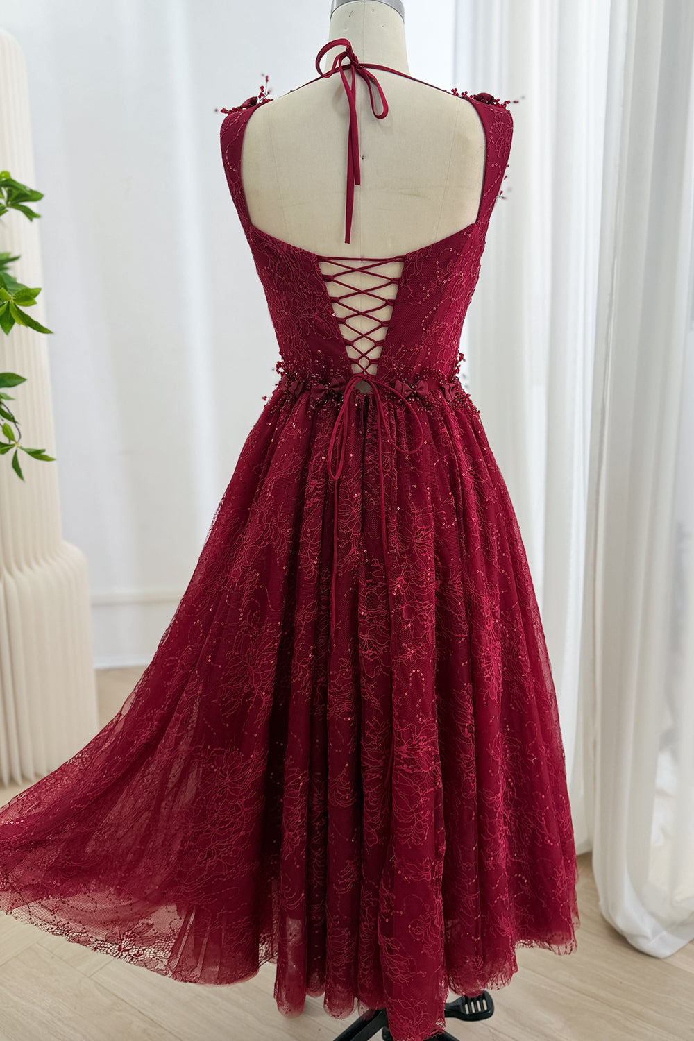 Full back view of the burgundy tea-length lace dress with open corset back and full A-line skirt