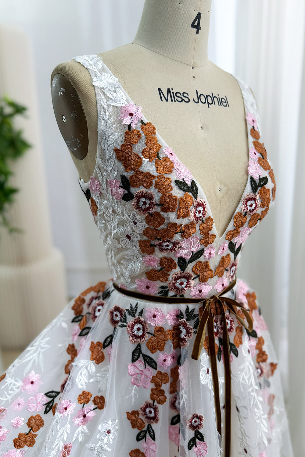 Close-up side view of pink, rust, burgundy, ivory, and green floral embroidery on the V-neck tulle bodice