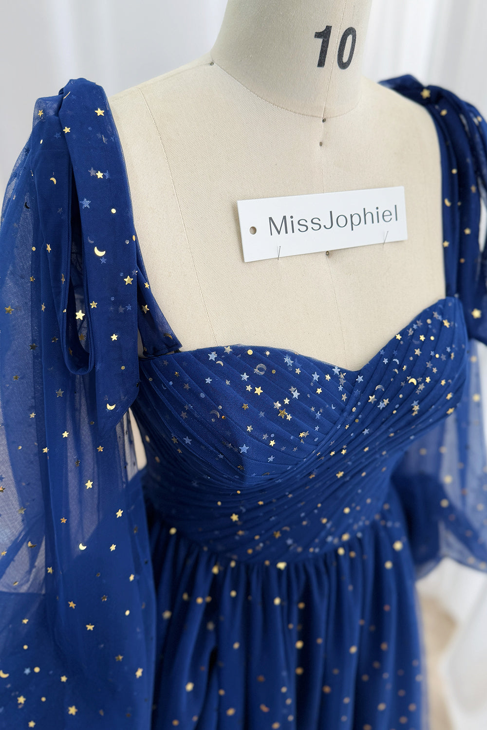 Detail of the ruched sweetheart neckline and metallic celestial pattern on dark navy tulle