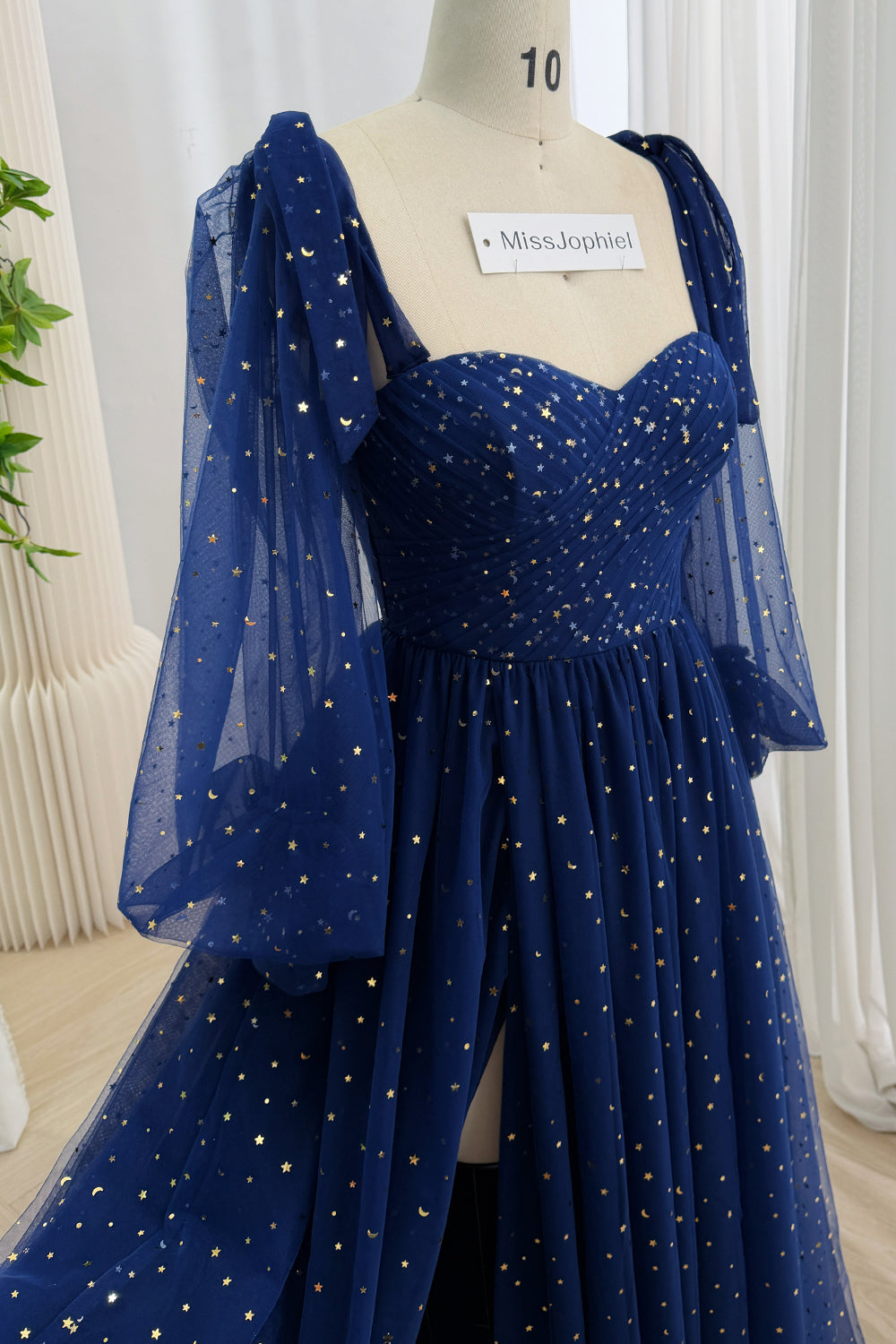 Close view of a dark navy celestial tulle gown with a ruched sweetheart bodice and sheer bell sleeves